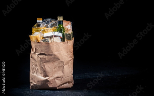 Fototapeta Paper bag with products on a dark background. Food donations