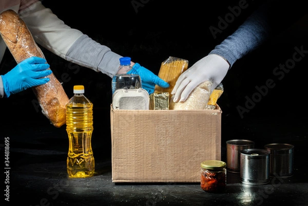 Fototapeta Volunteers putting different products in donation boxes on dark background