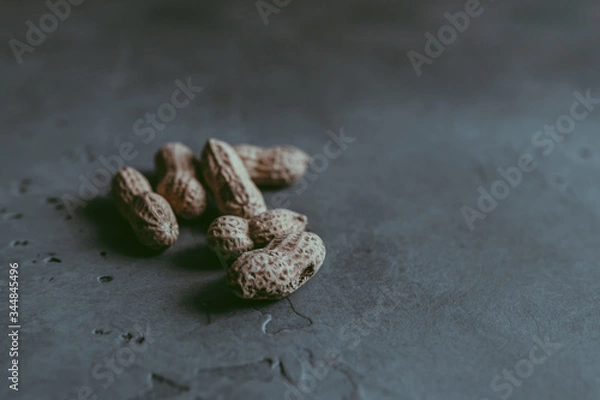 Fototapeta A close-up of a group of whole unpeeled dried peanuts in shell on a concrete blue textured background. A culinary and concept. Copy space. Soft focus. Natural background