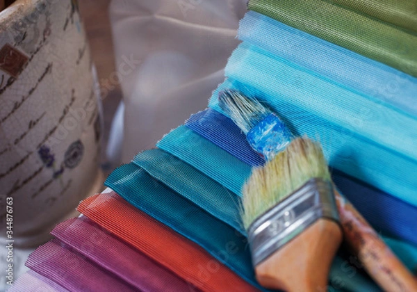Fototapeta colorfull textile lies on a colorfull palette of the artist.Colored brushes and fabrics.