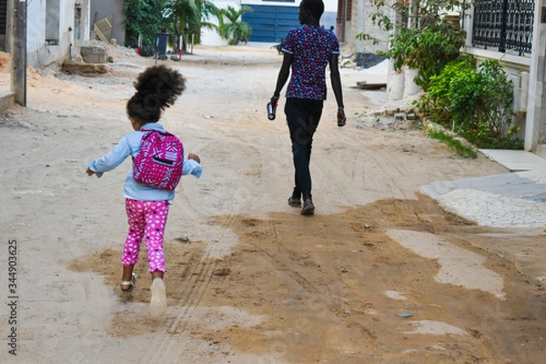 Fototapeta Dakar, Senegal, Africa, February, 2020: Senegalese girl with curly hair, ready to go to school in poor area