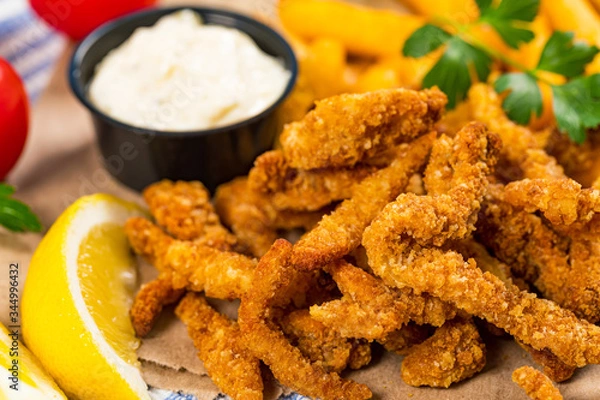 Fototapeta Crispy Breaded Clam Strips Snack Size. Deep Fried Breaded Clams Fingers with Tartar Dipping Sauce. Selective focus.