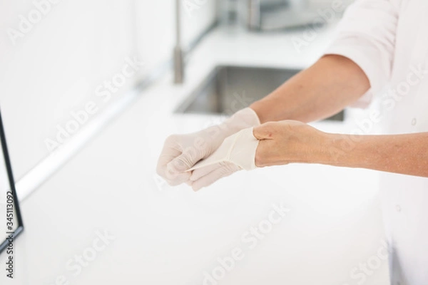 Fototapeta Frau zieht Latexhandschuhe an