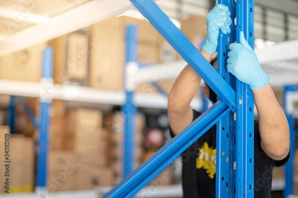 Fototapeta Male hand holding prepare to assembling the metal rack  in warehouse or storage and shelves for cardboard boxes of products.