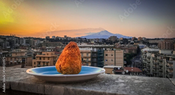 Fototapeta Arancino on a plate with landscape and the city behind it