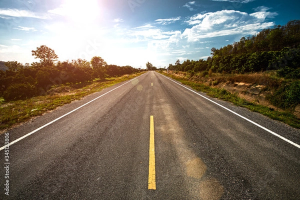 Fototapeta Empty asphalt road through the green field and clouds on blue sky in summer day.