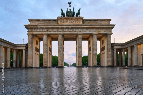 Fototapeta berlin germany, deserted brandenburg gate with reflections on the wet asphalt and with clouds at the sunset. special perspective as close-up from the ground, 