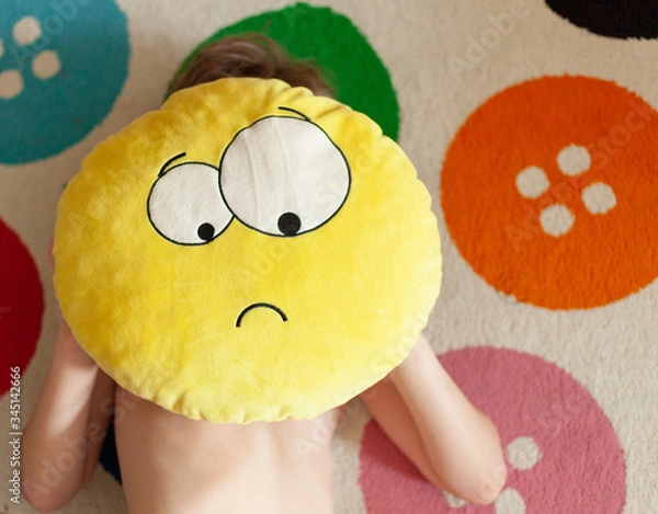Fototapeta pillow sad emoji child holds hands, background carpet with colored buttons