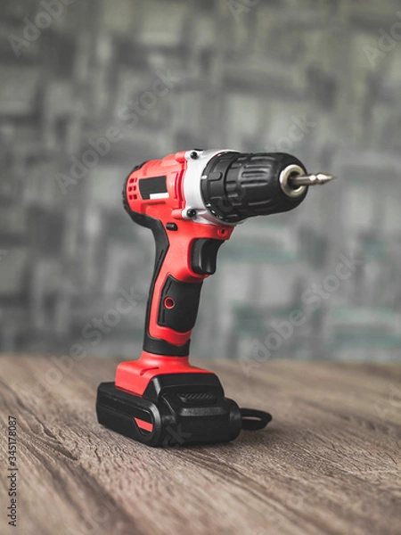 Obraz red electric screwdriver close up lying on a wooden table.