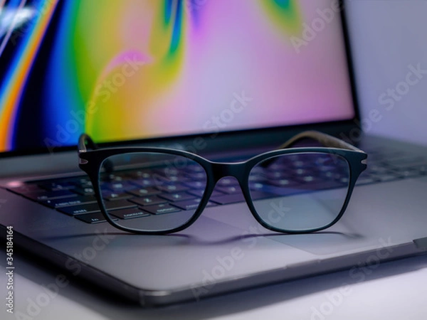 Fototapeta Blue light blocking glasses on the laptop. Black frame glasses for filtering blue light from the computer. Prevent Computer Vision Syndrome. Eye protection from PC screen