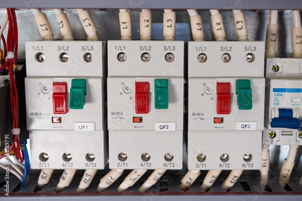 Fototapeta Three automatic motor protection switches with connected wires in the electrical Cabinet. The switches are arranged in a row. There is an adjustment of the current of the electric load.