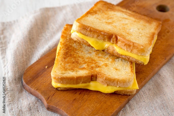 Fototapeta Homemade Grilled Cheese Sandwich on a rustic wooden board, low angle view. Close-up.