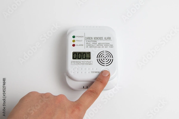Fototapeta testing carbon monoxide detector on a white wall. Stay home safe. Home control and security.  CO detector