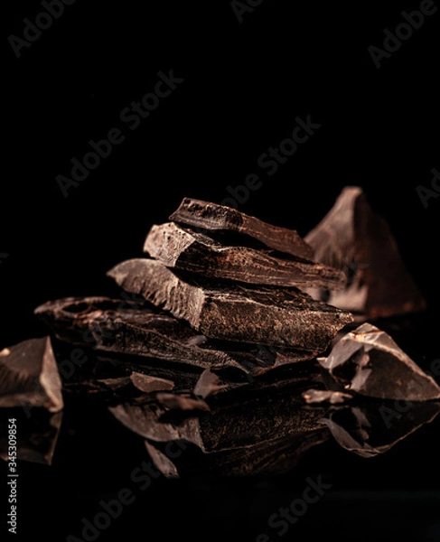 Fototapeta broken bar of dark chocolate on a dark background