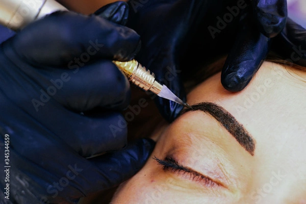 Fototapeta master brow artist makes permanent eyebrow makeup in the technique of powder browsers. Semi-permanent make-up