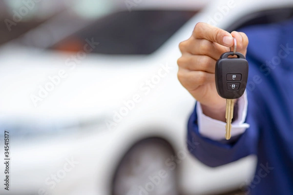 Obraz Close up of dealer giving key to new owner and shaking hands in auto show.