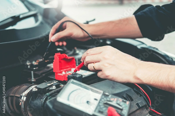 Fototapeta Auto mechanic working in garage Technician Hands of car mechanic working in auto repair Service and Maintenance car battery check.