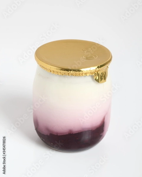 Fototapeta Yogurt with jam in small glass jar with aluminium foil seal cap.