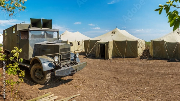 Fototapeta Retro german World War II military truck Krupp L3H163 is standing near a row of old canvas tents in a military camp