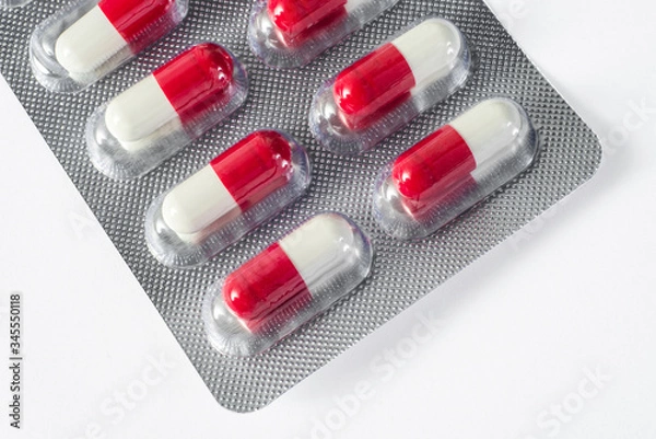 Obraz red white pills fall on a blue plate