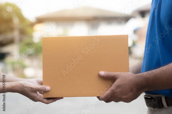 Obraz Woman hand accepting a delivery boxes of paper containers from deliveryman.