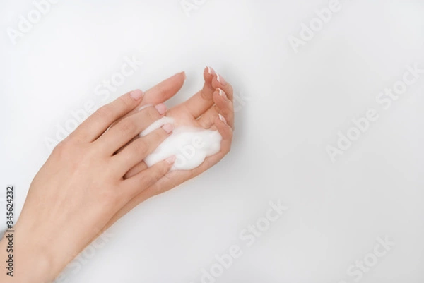 Fototapeta female hands apply foam on a white background