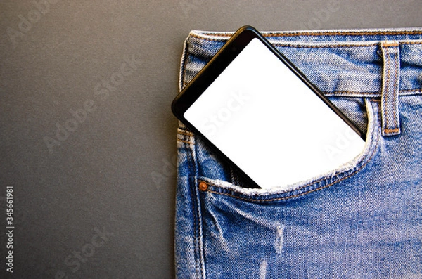 Fototapeta White screen smartphone in jeans pocket. Smartphone place for text. Smartphone in a pocket on a black background.  Copy Space