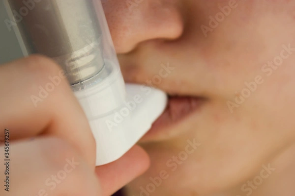 Fototapeta World Asthma Day May 5.anti-asthma inhaler on a blue background.teenager uses an inhaler