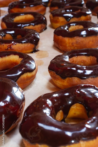 Fototapeta row of donuts coated with chocolate icing with a cup of black coffee