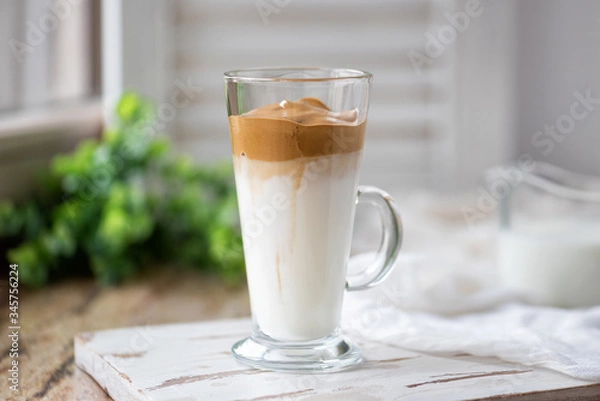 Fototapeta Dalgona coffee with ice and fluffy creamy whipped instant coffee on wooden tray. Trend korean drink latte on marble brown table