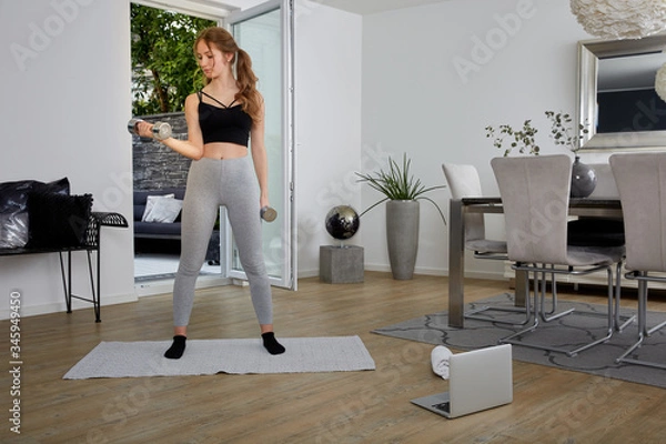 Obraz Frau macht Sport Training Zuhause mit Anleitung über das Notebook, Bizeps Training mit Kurzhanteln