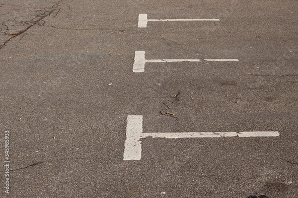 Fototapeta Old, dirty and fading white markings in a empty parking lot