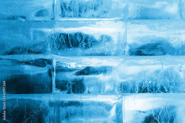 Fototapeta Large pieces of ice made in the form of a brick wall, transparent, illuminated by blue light. Structure, texture, background.