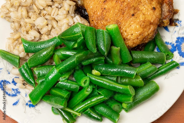 Obraz green asparagus beans on a plate with golden chicken thighs and pearl barley. healthy diet food.
