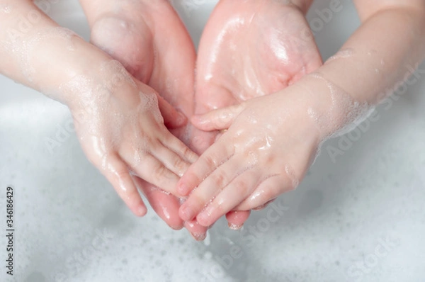 Fototapeta Mom washes hands with soap to her baby. Teaches a child how to wash hands with soap.