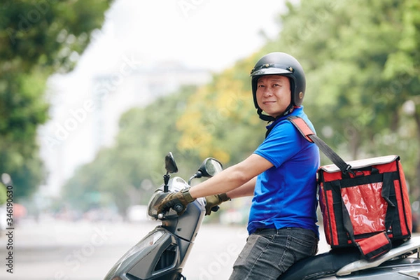 Fototapeta Portrait of cheerful Vietnamese man with big cooler bag working for delivery service