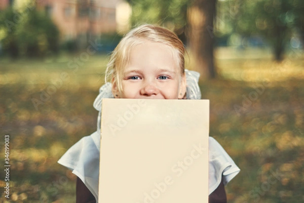 Fototapeta Portrait of a happy child hiding behind a book.