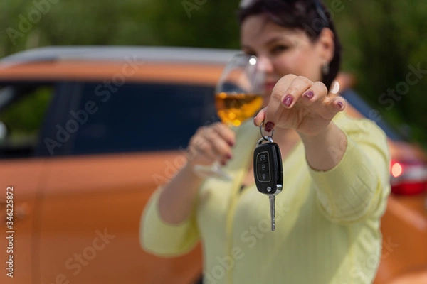 Obraz The concept of a designated driver. A girl with a glass of wine hands the car keys to a sober driver. Focus on the keys.