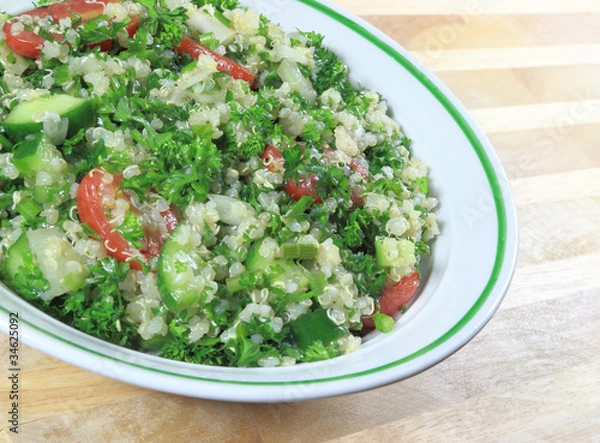 Fototapeta Quinoa Tabouleh salad in a bowl sitting on a wooden table.