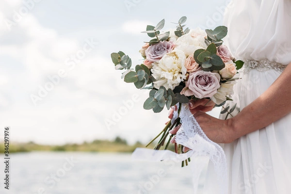 Obraz Bridal bouquet. Beautiful wedding pink and white flowers in hands of the bride. Close up outdoor shot against nature background. Wedding bouquet in bride's hands. Copy space