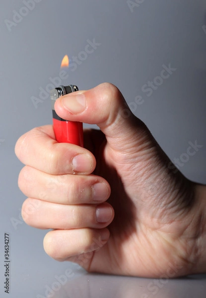 Fototapeta Hand igniting red cigarette lighter