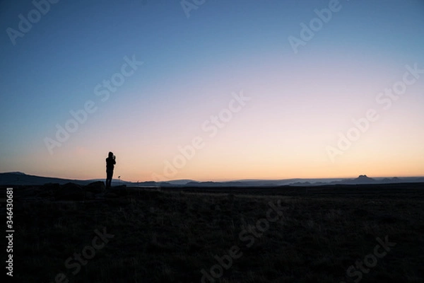 Fototapeta Silhouette of a person taking a photo of the horizon