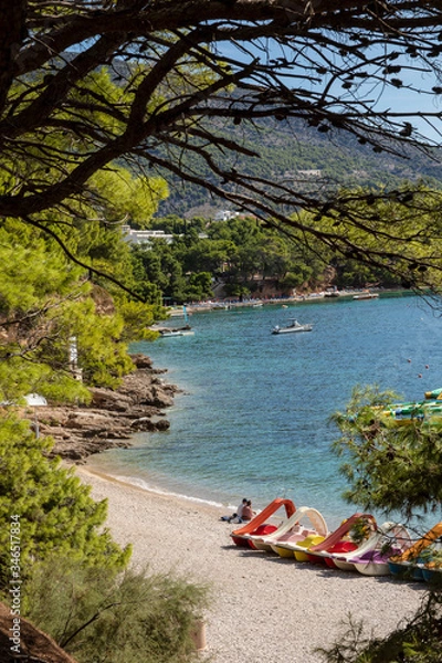 Obraz Bol beach on Brac island view with water cycles. With pebbles surrounded by pine trees, pines and greenery on a sunny day in summer in Dalmatia, Croatia. Clear blue Adriatic sea