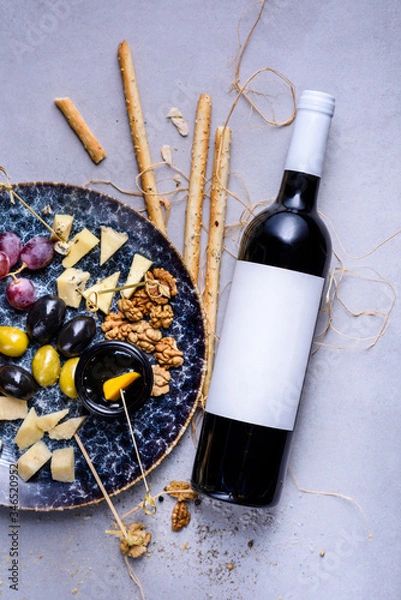 Obraz Cheese plate with grapes and olives. Snacks and cheese served with bottle of wine. Top view, copy space.