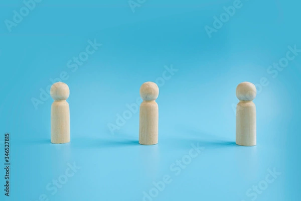 Fototapeta Wooden dolls on blue background with distancing represent to people practice social distancing to protect from COVID-19 coronavirus spreading. Social distance preventing infection concept.