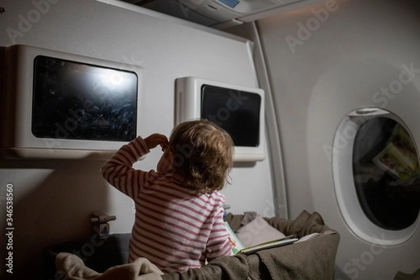 Obraz comfortable flight with infant. little cute toddler sitting looking at the screen