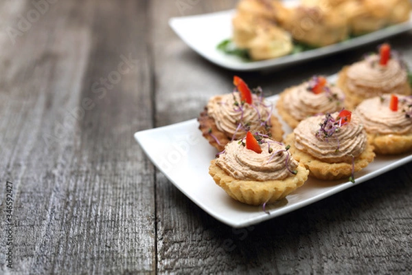 Obraz Shortbread muffins stuffed with tuna paste. A dry starter.
Appetizing dish on a wooden table.