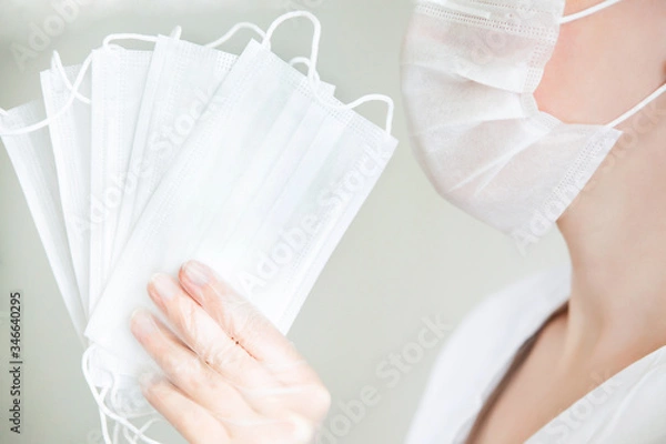 Fototapeta Several white protective masks in the left hand. Face mask on the right