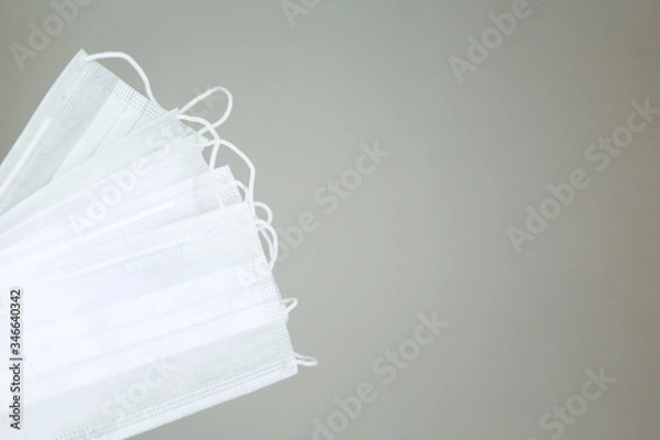 Fototapeta Several white protective surgical masks on a gray background on the left