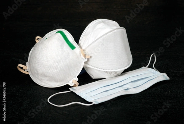 Obraz Three styles of N95 medical face masks for use to protect against contamination of respiratory infection, commonly used to protect agains the spread of COVID-19 virus, set against a black background.